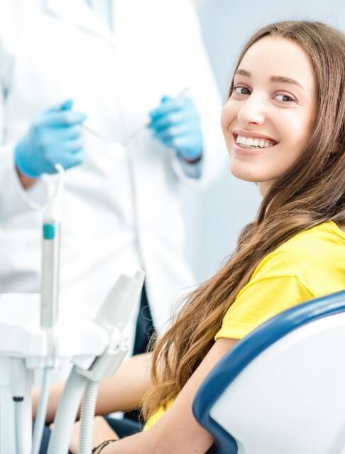 Young woman in yellow blouse smiling in dental chair