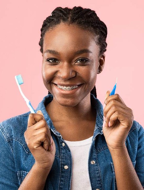 Woman with traditional braces in Castle Rock, CO holding toothbrush