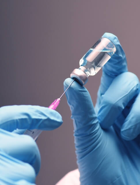 Dentist drawing a syringe from a vial of clear liquid