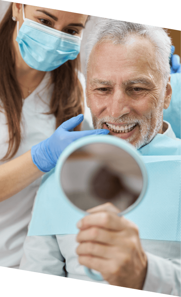 Senior dental patient admiring his smile in mirror after getting dental implants in Castle Rock