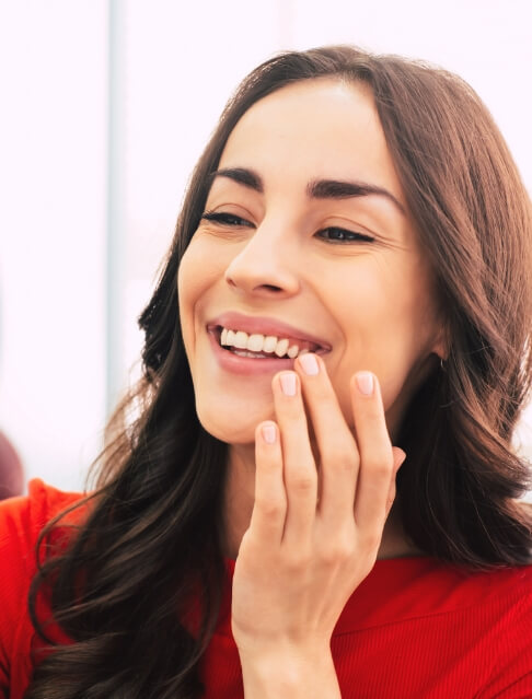 Young woman in dental chair looking at her smile in mirror