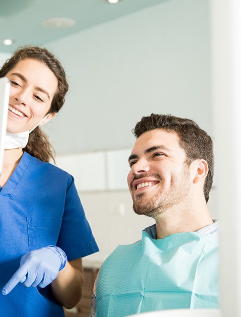 Smiling patient holding up clear aligners