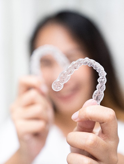 Dentist with blue gloves holding clear aligner