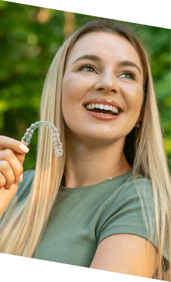 Woman holding clear aligner for orthodontics in Castle Rock