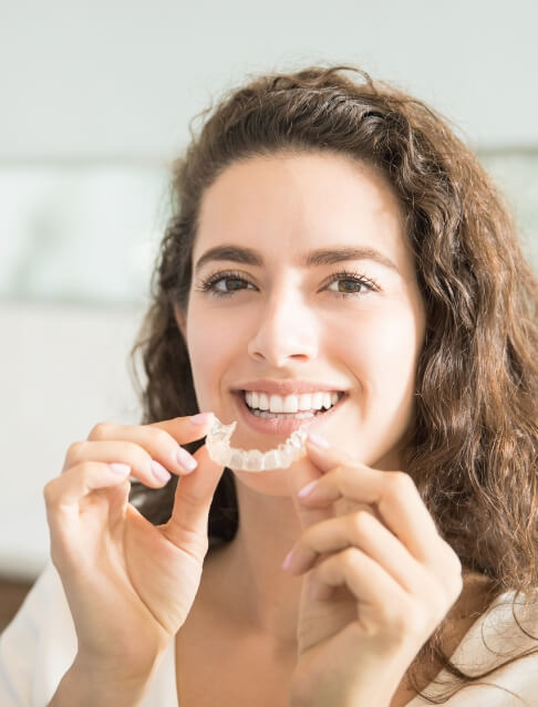 Woman placing a clear aligner in her mouth