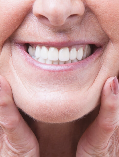 Close up of smiling senior woman touching her face