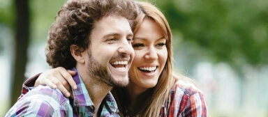 Smiling young man and woman hugging outdoors