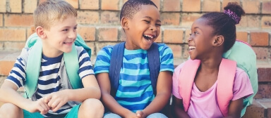 Three kids wearing backpacks and laughing together