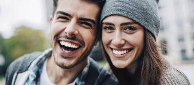 Laughing man next to smiling woman in gray beanie