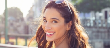 Woman with sunglasses grinning outdoors on sunny day