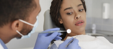 Woman looking scared as dentist prepares to give her a dental exam