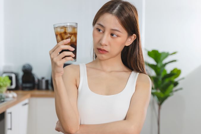 A woman looking at a glass of soda.